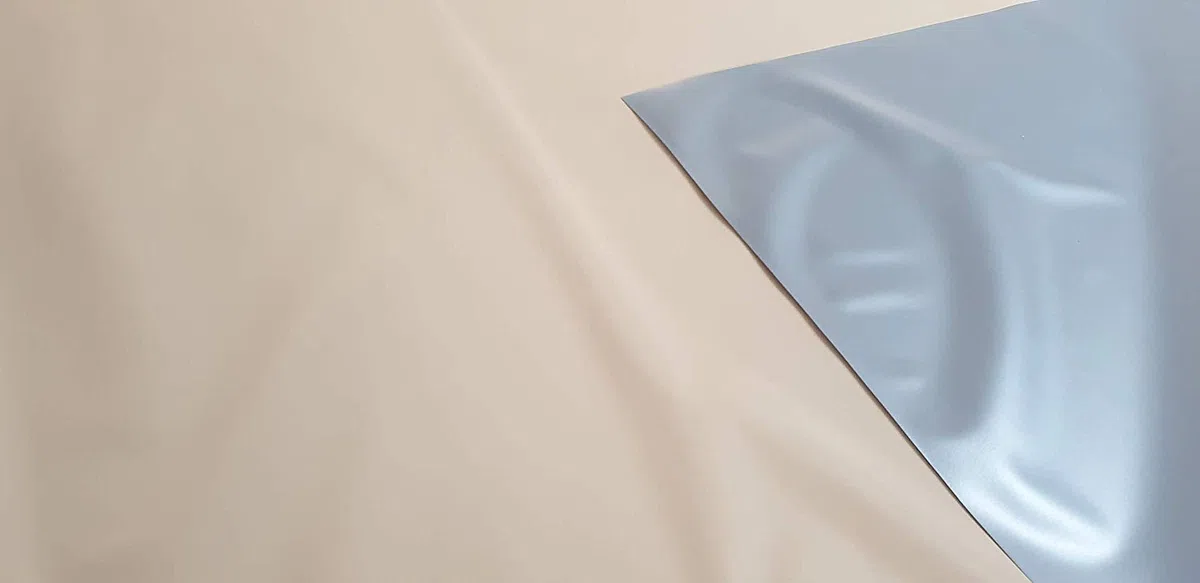PVC impermeable, pvc opaco y ignifugo. Ancho de 210 cm. Por una cara de color gris y por la otra de color beig